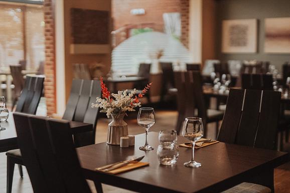 Cleaver Restaurant at the Cabarfeidh Hotel in Stornoway with tables and chairs in front of a brick wall.