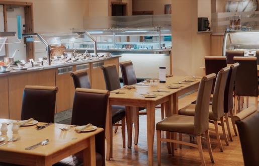 Spacious restaurant with carvery filled with numerous tables and chairs.