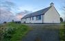 Am Bliochan self catering cottage north uist - exterior view from driveway with a red sky.