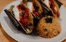 Three roasted vegetable tacos with rice and sauce on a white plate.