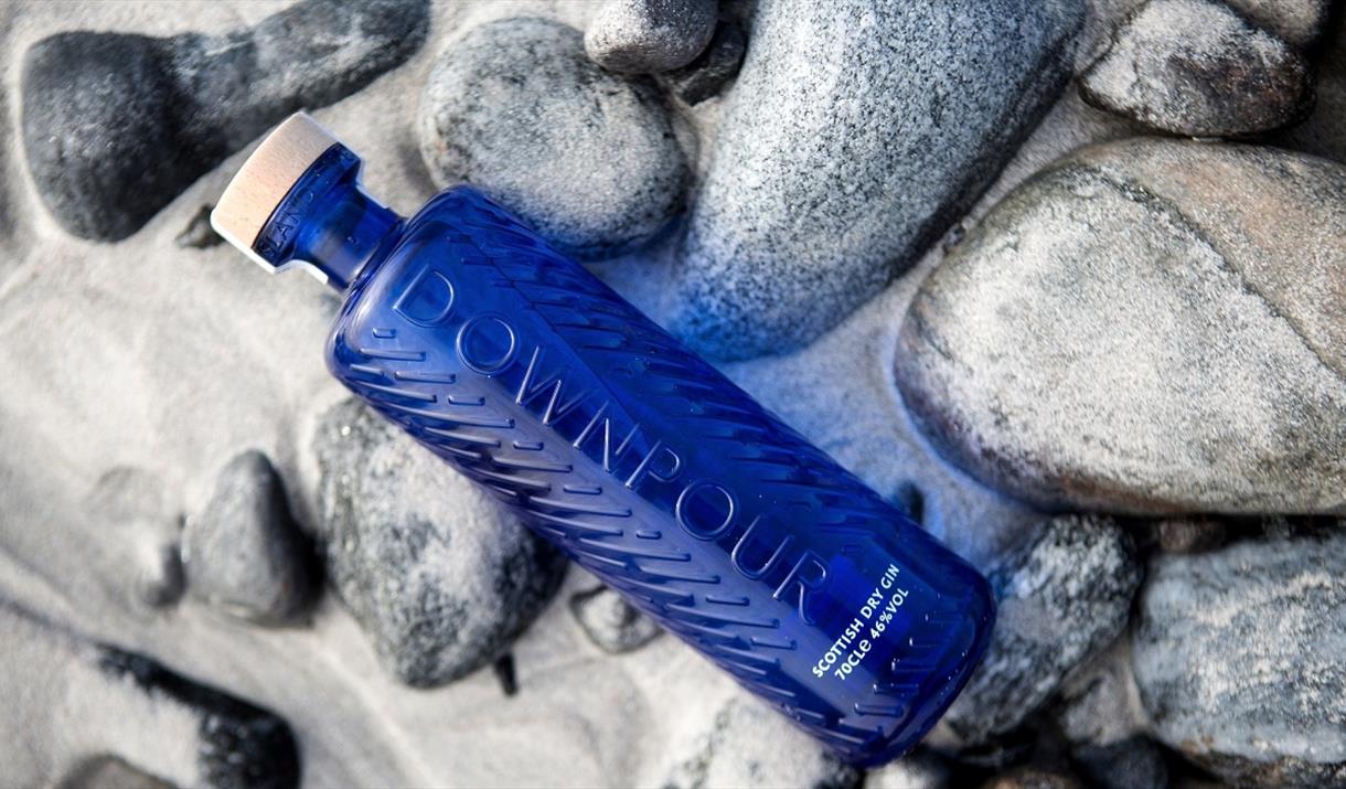North Uist Distillery's Scottish Dry Gin, sitting on white sand, overlooking the sea North Uist Distillery's Scottish Dry Gin, sitting on white sand, overlooking the sea